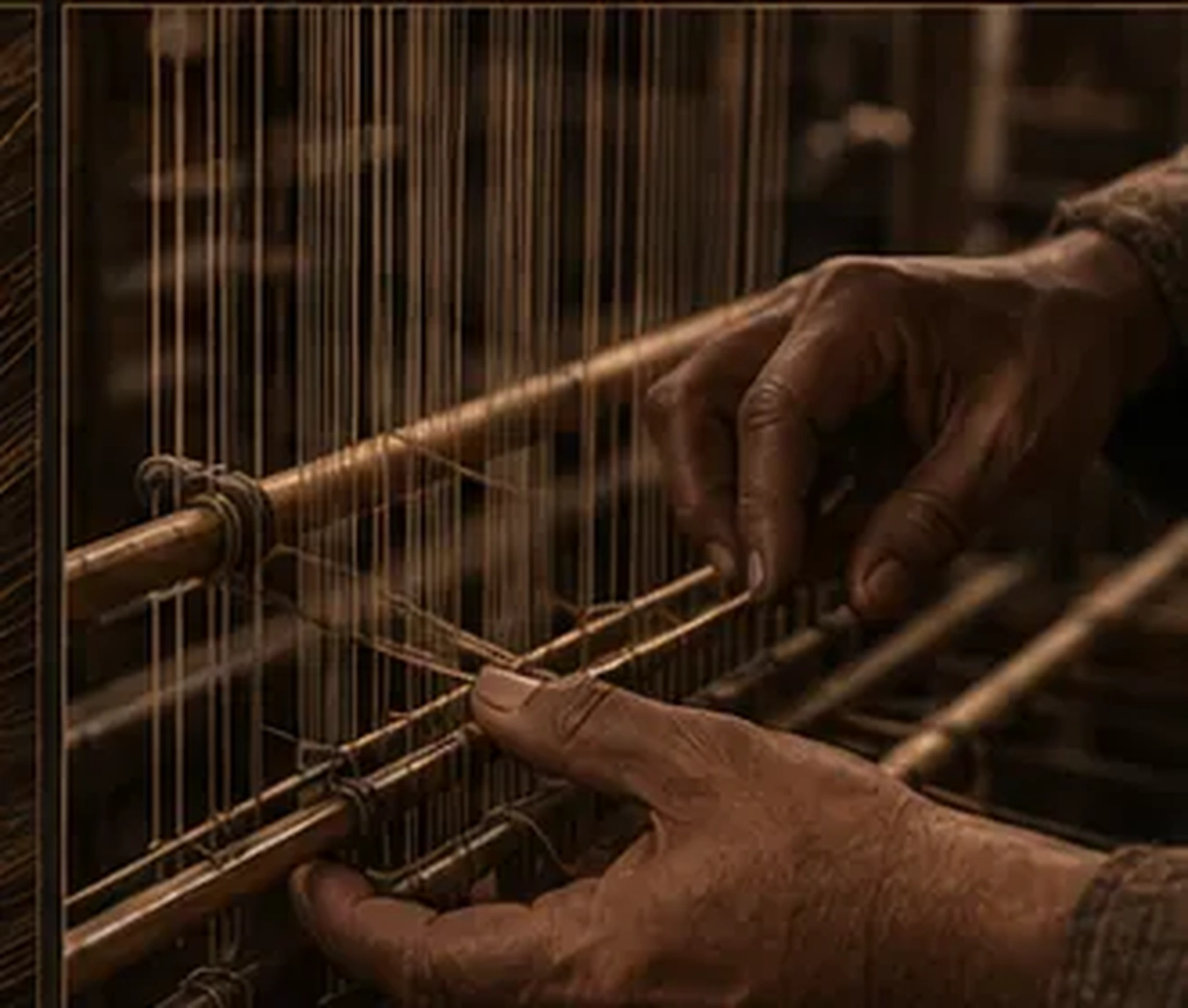 Hands guiding threads through a traditional loom